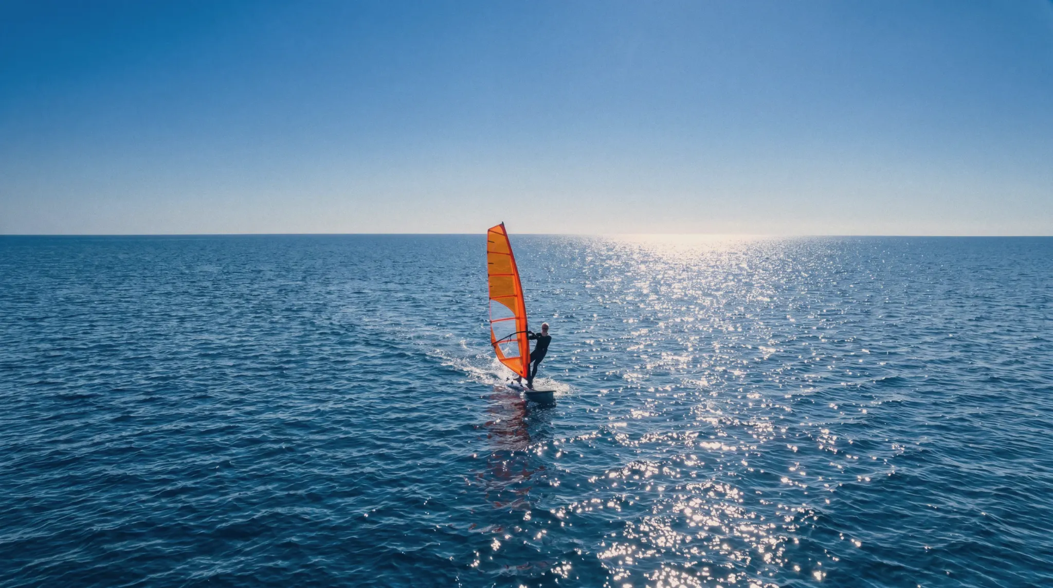 Windsurfer crossing a bright open sea